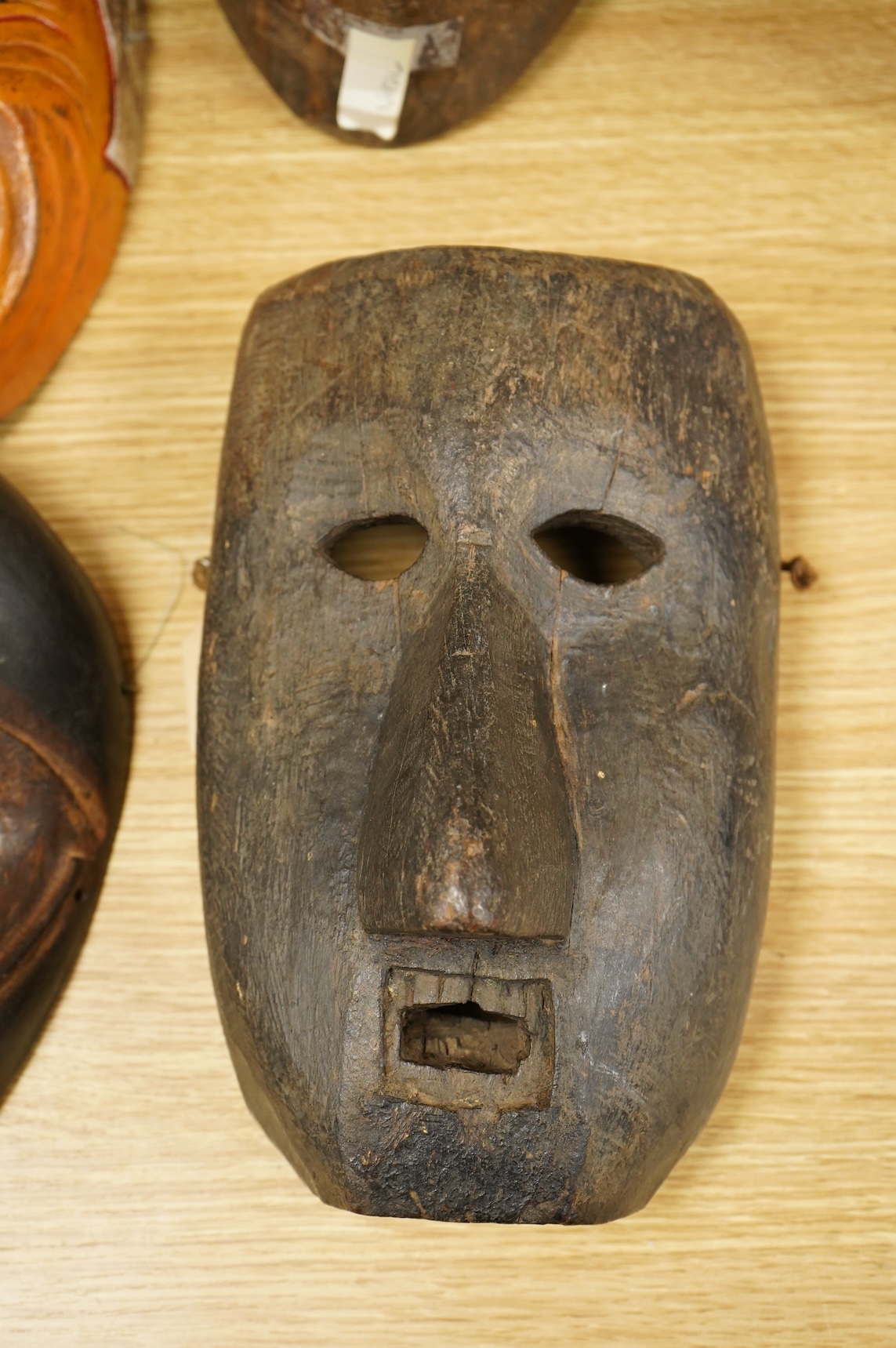 A collection of seven Nepalese, African and Indonesian masks to include a Magar example and one from the Dan Tribe, Liberia, largest 40cm